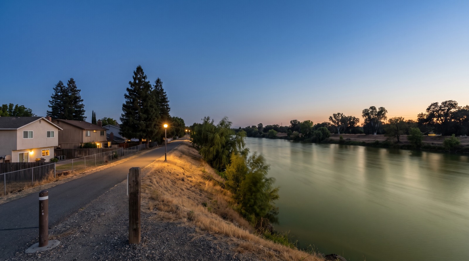 The Sacramento River at Garcia Bend in the Pocket neighborhood at blue hour, seen from the levee trail beside homes